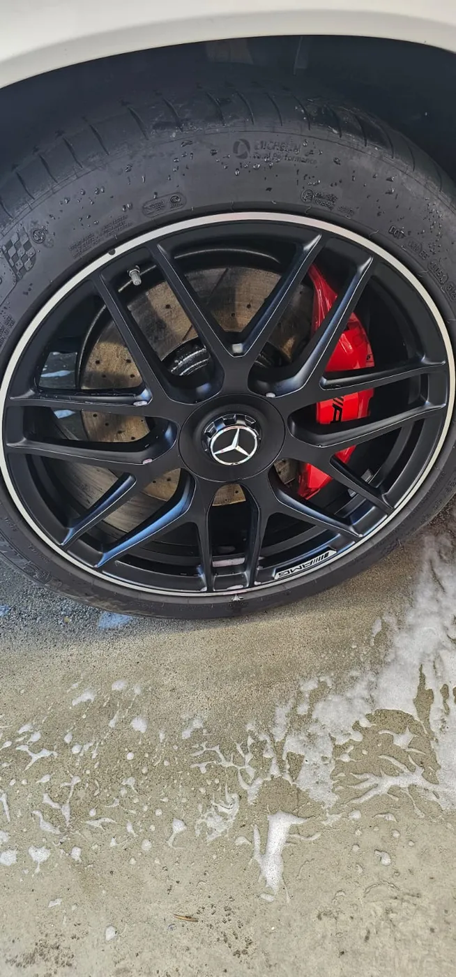 Mattschwarze AMG-Felge mit rotem Bremssattel nach der Aufbereitung
