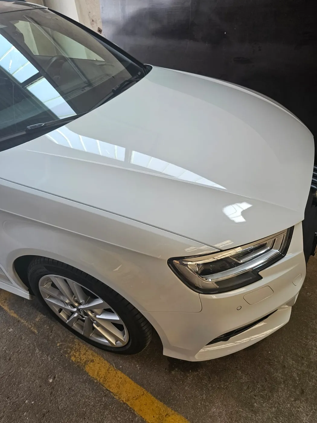 Weiße Audi-Front mit spiegelnder Motorhaube nach der Politur
