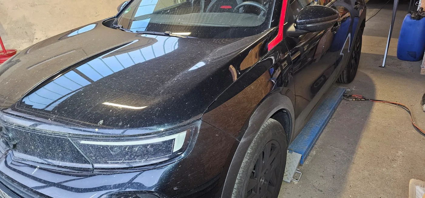 Schwarzer Opel Mokka vor der Aufbereitung: stumpfer, staubiger Lack auf Motorhaube und Kotflügel