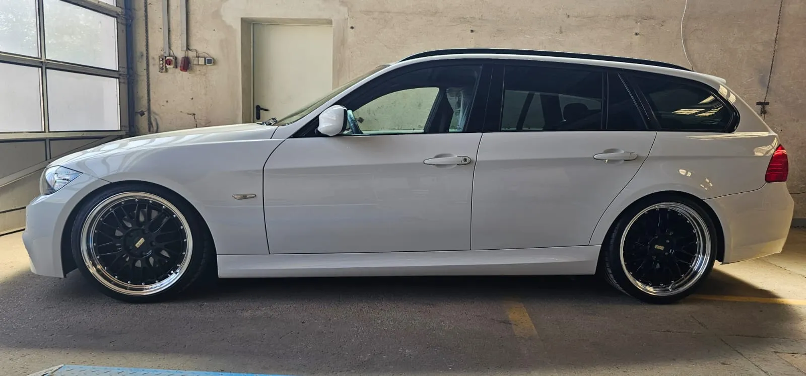 Frisch aufbereiteter weißer BMW Kombi in der Seitenansicht in der Werkstatt